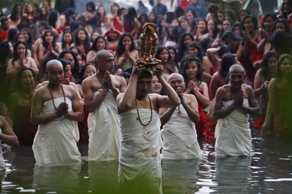A Nepalese Hindu priest, center, carries the idol of a deity as devotees gets ready to take holy dips at the Salinadi River on the first day of Madhav Narayan festival, in Sankhu, northeast of Katmandu.
