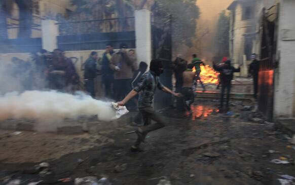 An Egyptian protester runs holding a tear gas canister to throw it back at riot police, not seen, during clashes near Tahrir Square, Cairo, Egypt.