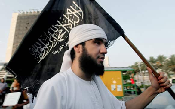 A Libyan follower of Ansar al-Shariah Brigades chants as he carries the Brigades flag, with Arabic writing that reads,