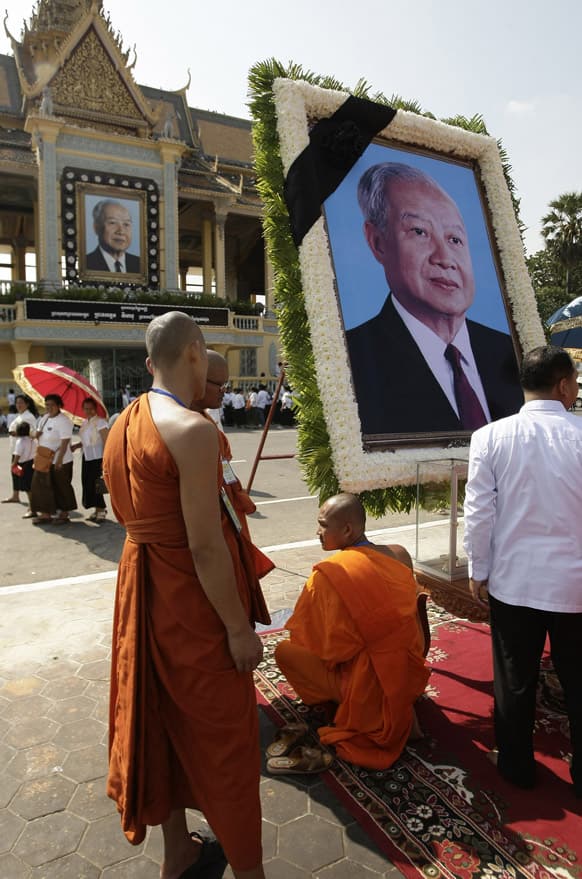 Buddhist monks, left, place a portrait of Cambodia`s late King Norodom Sihanouk, right, in front of the Royal Palace in Phnom Penh, Cambodia.