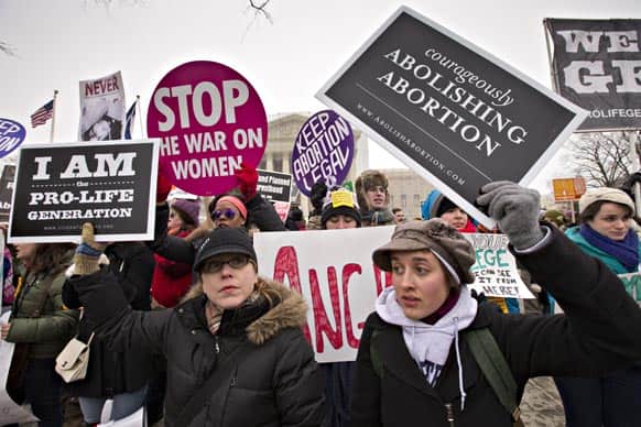 Anti-abortion activists and supporters of legal abortion stand in front of the Supreme Court in Washington.