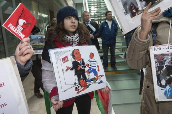 A pro Palestinian demonstrator holds a cartoon of Platini and she shouts slogan