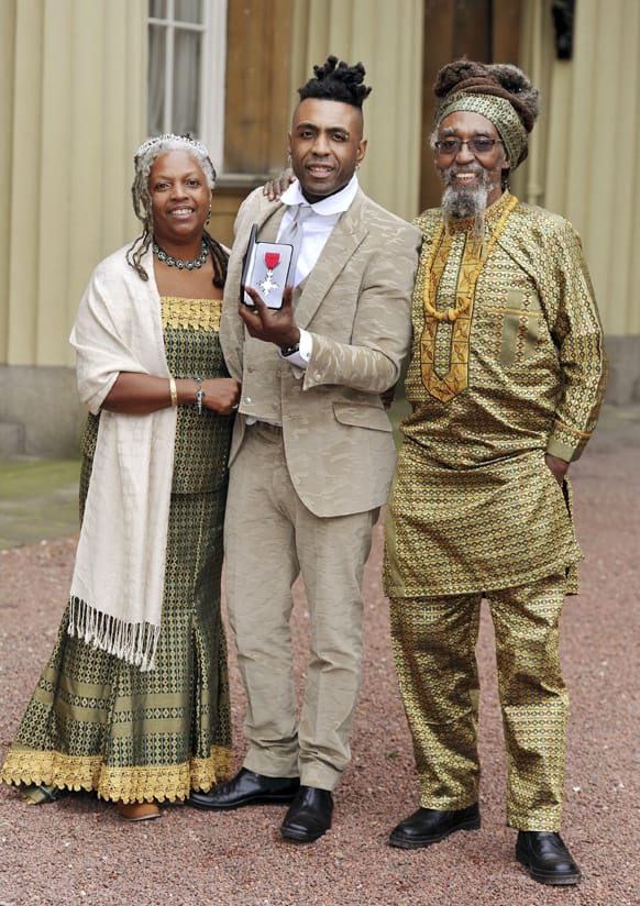 British musician Omar Lye-Fook, centre, with his parents Sonia and Byron, displays his Member of the British Empire (MBE) medal after it was presented to him by the Prince of Wales during the Investiture ceremony at Buckingham Palace in central London.