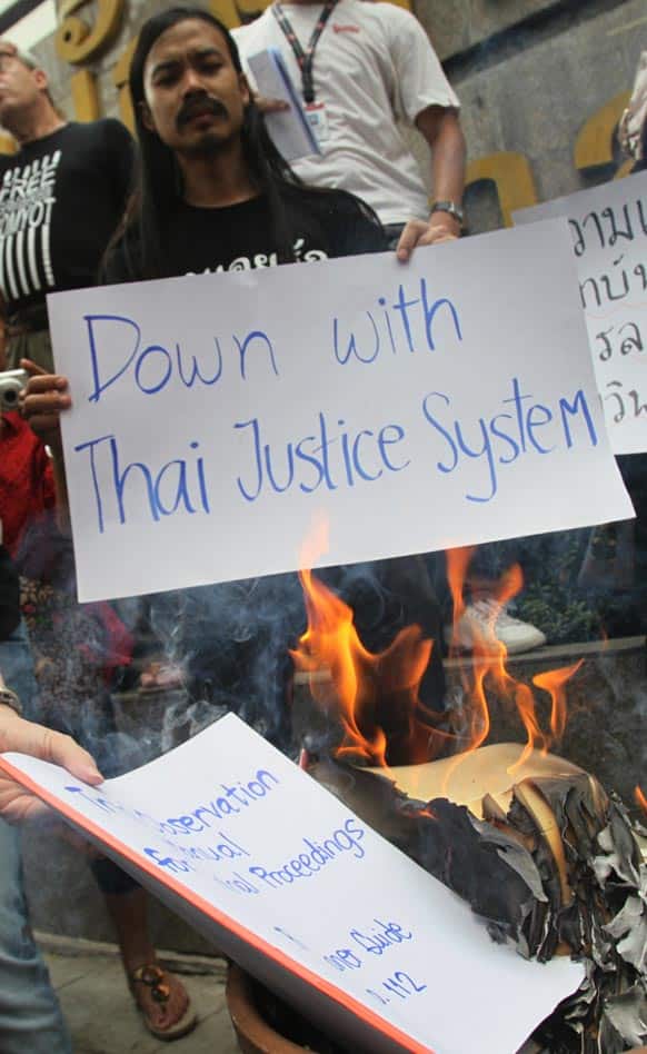 Protesters burn books of laws and show placards during a protest rally in front of the Criminal Court in Bangkok,Thailand.