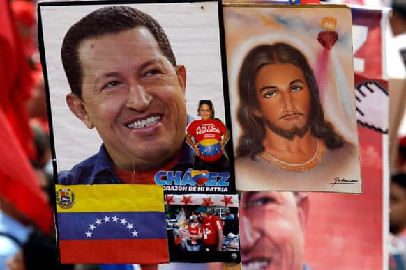 A photograph of Venezuela`s President Hugo Chavez flanks one of Jesus Christ, held by a Chavez supporter at a rally in Caracas, Venezuela.
