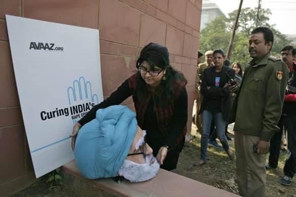 An activist removes the mask of Indian Prime Minister Manmohan Singh after police asked them to leave as they try to stage a protest outside a district court where the men accused in the gang rape and murder of a 23-year-old student are undergoing trial, in New Delhi.