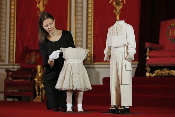 A Buckingham Palace employee poses with the outfits worn by the four-year-old Prince Charles and the two-year-old Princess Anne at Britain`s Queen Elizabeth II`s Coronation on June 2, 1953, during a photo opportunity at the Throne Room of Buckingham Palace in central London.