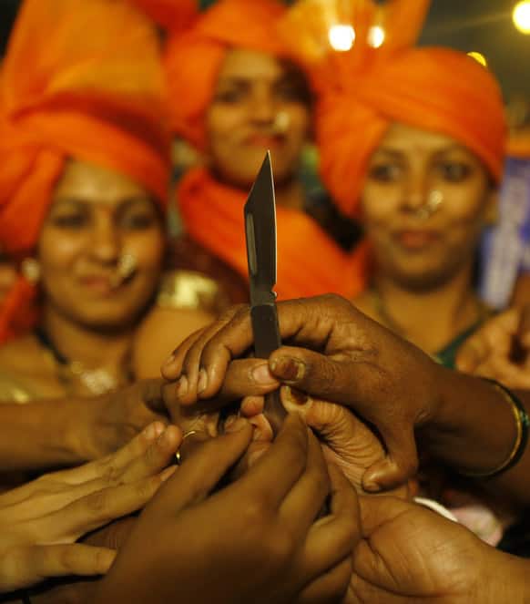 Women reach out their hands to collect knives being distributed by local leaders of Shiv Sena, a right-wing party in Mumbai.