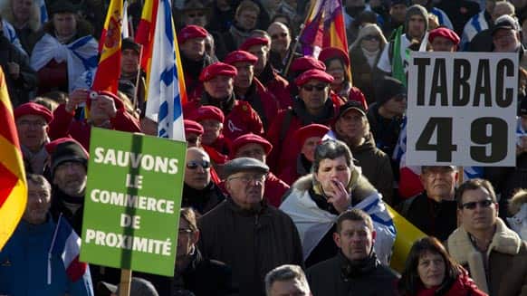 A man, center right, smokes a cigar as he stands with demonstrators marching against EU tobacco regulations in front of EU headquarters in Brussels.