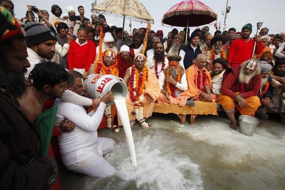 Hindu holy men, pour milk into the waters as they performs rituals at Sangam, the confluence of the rivers Ganges and Yamuna during the Maha Kumbh festival in Allahabad.