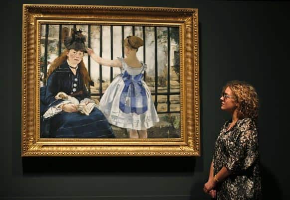 A Royal Academy of Arts employee poses for photographers in front of Manet’s oil on canvas painting entitled `The Railway, 1873` at the gallery in central London.