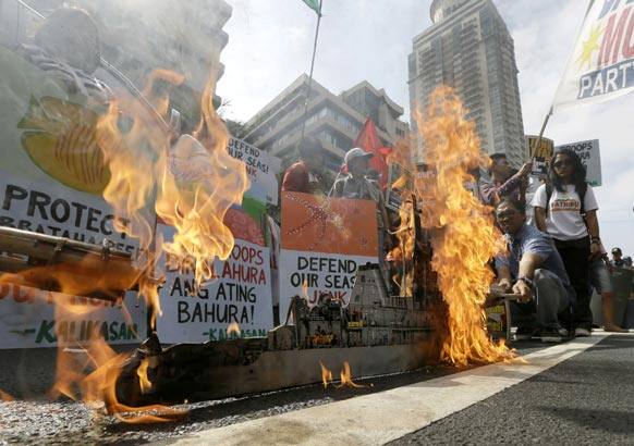 Protesters set fire to a mock model of the USS Guardian, a US Navy minesweeper which ran aground off Tubbataha Reef in southwestern Philippines, during a rally near the US Embassy in Manila to demand US troops pull out from the country.
