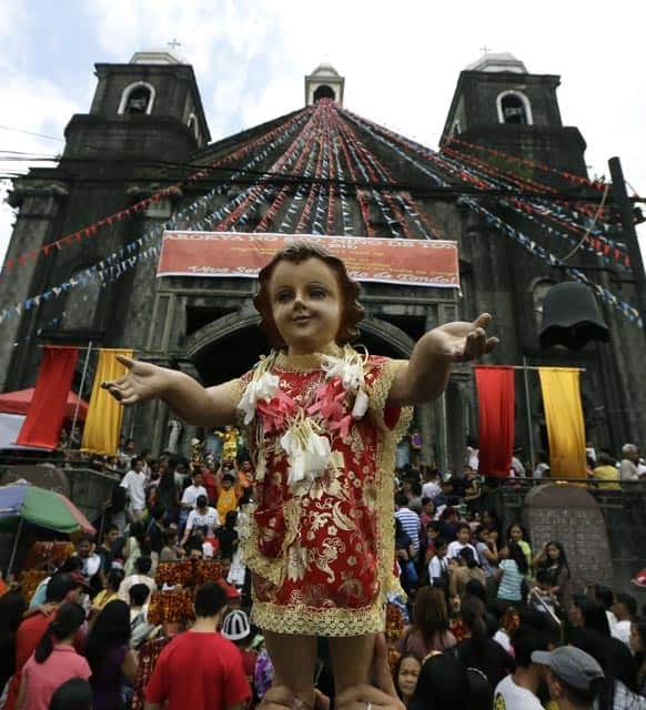 Hundreds of Roman Catholic devotees raise their images of the Infant Jesus to be blessed during a mass to celebrate its feast day at Manila.
