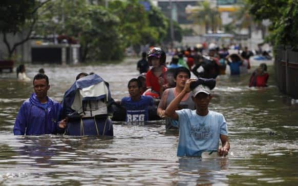 People wade through a flooded street in Jakarta. The death toll from floods in Indonesia`s capital has climbed to 14 after searchers pulled three more bodies from the waters.