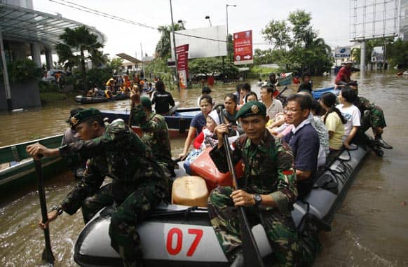 Indonesian soldiers help evacuate people in a rubber boat in Jakarta. The death toll from floods in Indonesia`s capital has climbed to 14 after searchers pulled three more bodies from the waters.