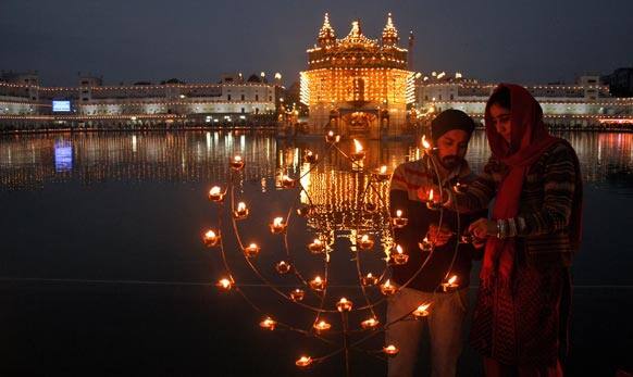 A Sikh couple lights lamps in the grounds of the Golden Temple, Sikh`s holiest temple, illuminated to celebrate the birth anniversary of Guru Gobind Singh in Amritsar.