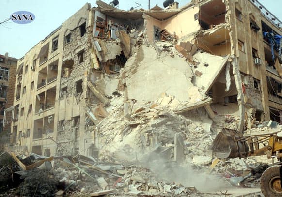 This photo released by the Syrian official news agency SANA, shows damage after a rocket slammed into a building, killing at least 12 people, in Aleppo, Syria.