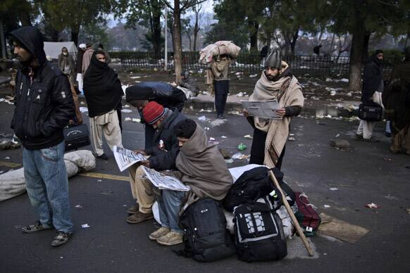Supporters of Pakistani Sunni cleric Tahir-ul-Qadri sit on their belongings while waiting for transportation, at the site where they were camping and attended an anti-government rally, in Islamabad, Pakistan.