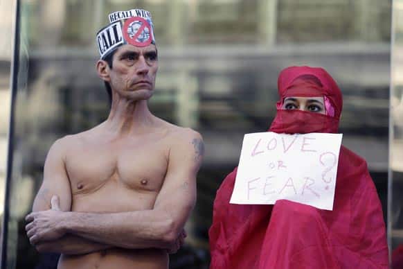 Natalie Mandeau, right, of France, holds up a sign during a demonstration against a nudity ban outside a federal building, in San Francisco.