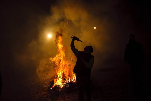 A man drinks wine near a bonfire in San Bartolome de Pinares, Spain, in honor of Saint Anthony, the patron saint of animals.