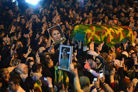 Kurds shout slogans to praise three women activists who were found shot dead in Paris, as one of their coffins is carried at an airport in Diyarbakir, southern Turkey.