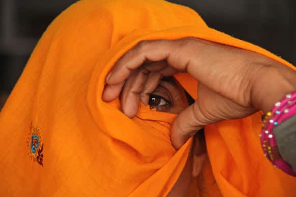 An Indian Rajasthani woman peers out from her veil as she waits for a train to return home after attending the Maha Kumbh festival, at a railway station in Allahabad.