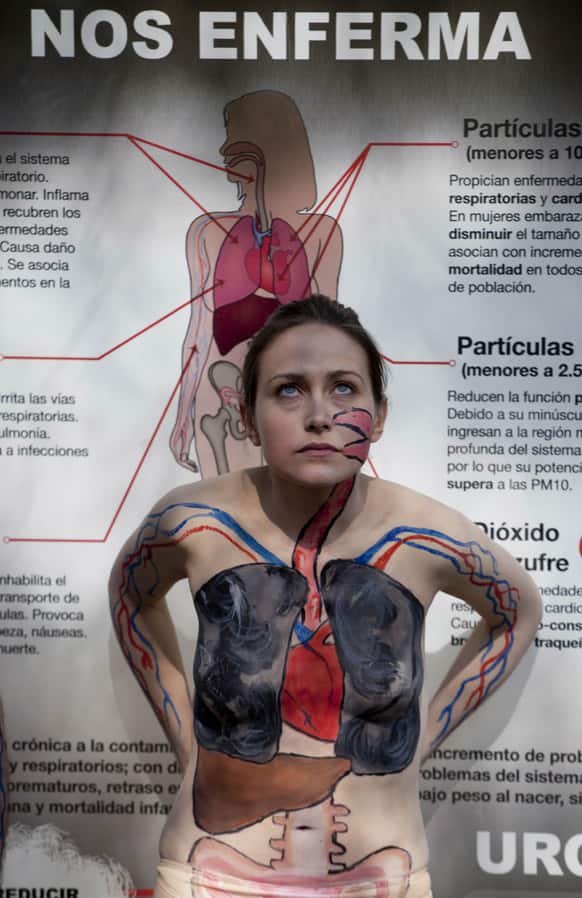 An activist wearing body paint that illustrates her organs damaged from air pollution stands in front of a poster that reads in Spanish