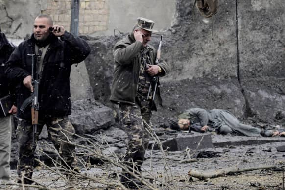 Security men talk on their cellphones at the scene, which was attacked by militants in Kabul. Six militants wearing suicide vests including one driving a car packed with explosives attacked the gate of the Afghan intelligence in Kabul.