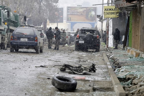 A security official with the Afghan intelligence services, center, investigates the scene of a suicide car bomb attack in Kabul, Afghanistan.