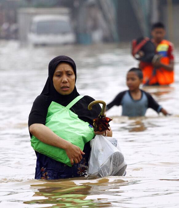 A woman wades through floodwaters in Jakarta, Indonesia. Flooding caused by monsoon rains have forced thousands of people to flee their homes in Indonesia`s capital.