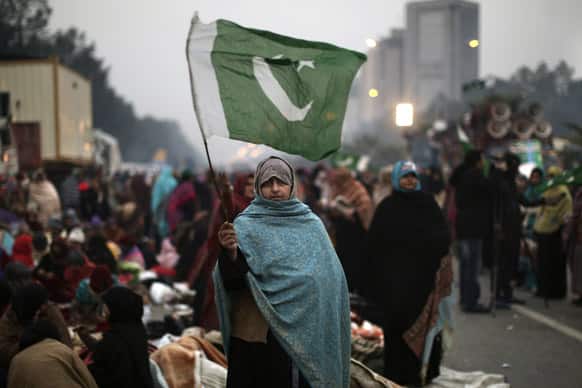 A supporter of Pakistani Sunni Muslim cleric Tahir-ul-Qadri, waves a national flag while she and others camp near parliament, during an anti-government rally in Islamabad.