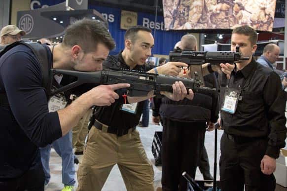 Firearms instructors Logan Martin, left, and Andres Gonzalez, of Calgary, Alberta, look through the sights of Sig Sauer Swat Patrol AR rifles during the 35th annual SHOT Show.