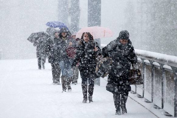 Pedestrians walk through the snow protected by their umbrellas during heavy snowfalls, in Geneva, Switzerland.