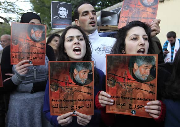 Supporters of Lebanese Georges Ibrahim Abdullah, who has been jailed in France for 28 years, holds up his portrait with Arabic that reads,