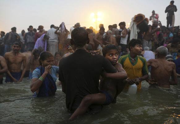 Hindu boy is held by his father as they go for a dip at Sangam, the confluence of the rivers Ganges, Yamuna and mythical Saraswati, during the royal bath on Makar Sankranti at the start of the Maha Kumbh Mela in Allahabad.