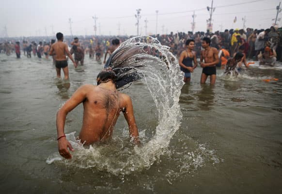 Hindu holy man, or Naga Sadhus, swings his hair as he bathes at Sangam, the confluence of the rivers Ganges, Yamuna and mythical Saraswati, during the royal bath on Makar Sankranti at the start of the Maha Kumbh Mela in Allahabad.