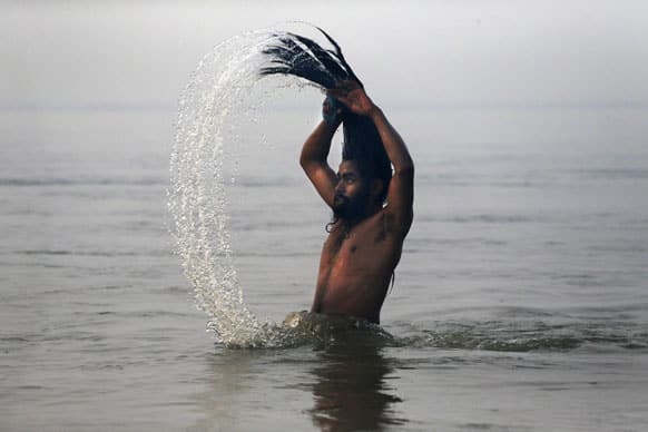 Hindu holy man, or Naga Sadhu, swings his head as he bathes at Sangam, the confluence of the rivers Ganges, Yamuna and mythical Saraswati, during the royal bath on Makar Sankranti at the start of the Maha Kumbh Mela in Allahabad.