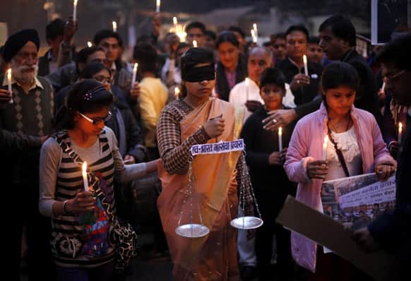An Indian girl, center, dressed as Lady Justice takes part in a candlelight vigil in New Delhi.