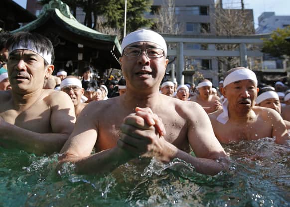 Japanese physical fitness enthusiasts pray while dipping in icy water during a winter ritual to keep themselves fit and display their perseverance at Teppozu Inari Shinto Shrine in Tokyo.