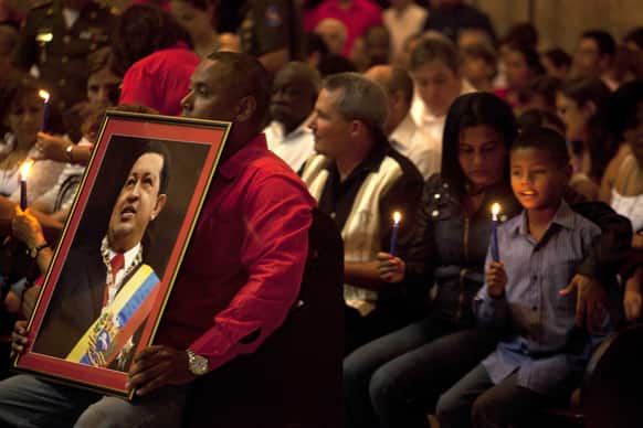 A man holds a framed image of Venezuela`s President Hugo Chavez during a Mass to pray for the recovery of Chavez at the Cathedral, in Havana, Cuba.