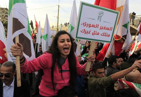 A Lebanese anti-Syrian regime protester holds an Arabic placard that reads,