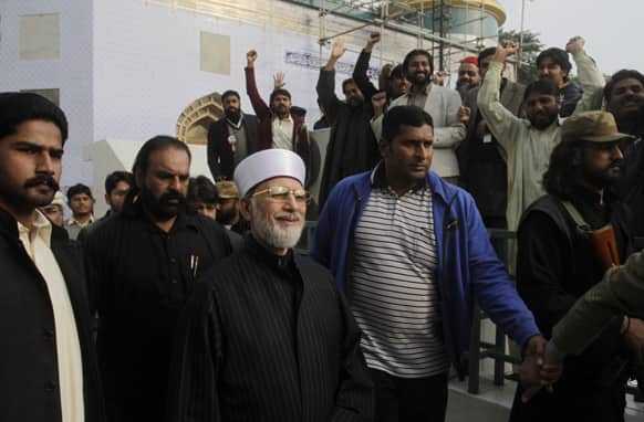 Pakistani cleric Tahir-ul-Qadri, center, surrounded by guards, is greeted by supporters after attending a press conference, in Lahore, Pakistan.