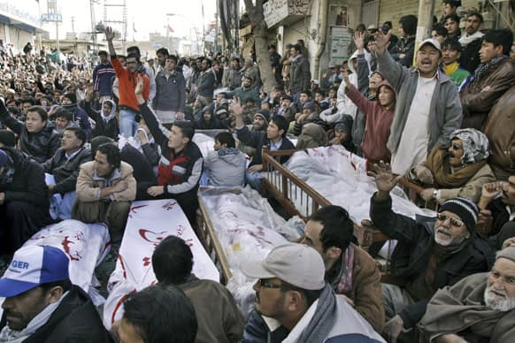 Pakistani Shiite Muslims sit next to bodies and await the burial of their relatives and friends who were killed in Thursday`s deadly bombings, during a protest in Quetta.