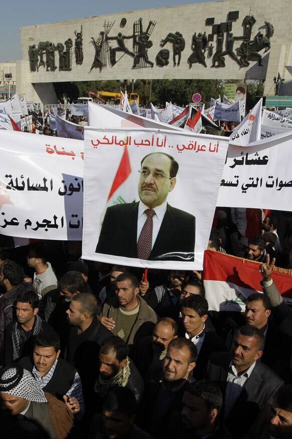 Shiite demonstrators chant pro-government slogans and wave national flags, to show support for Prime Minister Nouri al-Maliki, center in photo on banner, in Baghdad, Iraq.