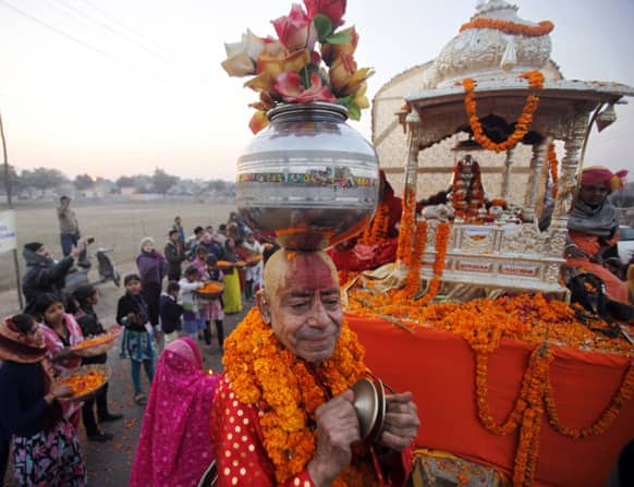 A Sadhu, or Hindu holy man, carries a pot containing artificial flowers on his head during a religious procession towards the Sangam, the confluence of rivers Ganges, Yamuna and mythical Saraswati, as part of the Maha Kumbh festival in Allahabad.