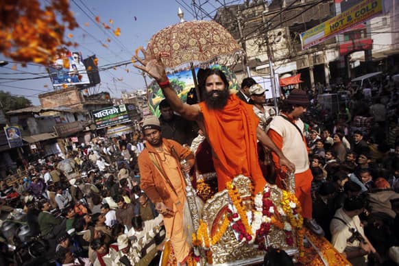 Yoga guru Baba Ramdev throws flower petals to devotees as he participates in a religious procession towards the Sangam, the confluence of rivers Ganges, Yamuna and mythical Saraswati, as part of the Maha Kumbh festival in Allahabad.