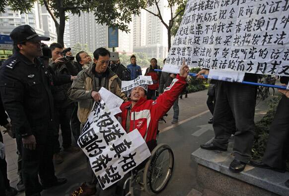 A policeman stands against a supporter in a wheelchair of the Southern Weekly during a protest before being taken away by the police near the Southern Weekly headquarters in Guangzhou.