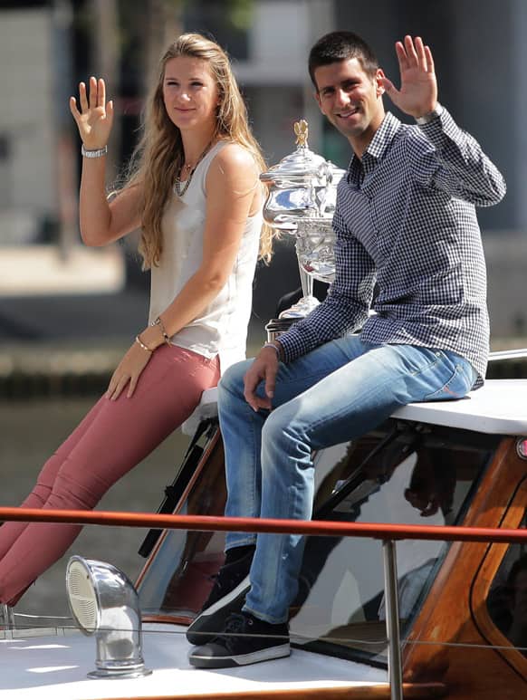Australian Open tennis championship defending women`s singles champion Victoria Azarenka of Belarus, left, and men`s singles defending champion Novak Djokovic of Serbia wave as they arrive with their trophies by boat at the official draw for the 2013 event in Melbourne.