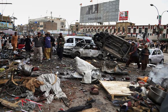 Pakistani police officers and local residents gather at the site of bomb blast in Quetta, Pakistan. A bomb targeting paramilitary soldiers killed scores of people in southwest Pakistan.