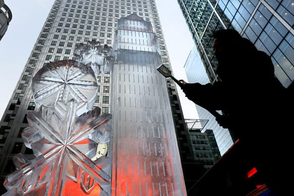 An ice sculpture is lit up by red light from an advertising screen as a sculptor works on it, in Canary Wharf at the official launch for the Ice Sculpting Festival in London. The London Ice Sculpting Festival runs from Jan. 11 until Jan. 13.